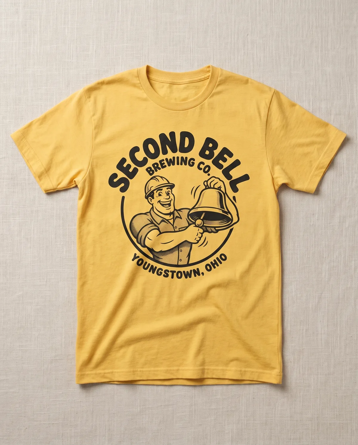 Cream tee with a 1950s cartoon foundry worker ringing a shift bell for Second Bell, Youngstown Ohio